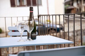 Un balcon avec une table, une bouteille de vin Ferrari Maximum et deux verres.