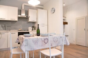 Een moderne keuken met witte kasten, een roestvrijstalen afzuigkap en een eethoek met een tafel gedekt voor twee personen.