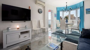 A modern living room with a flat-screen TV, a glass coffee table, and a sofa.