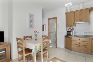 A kitchen with wooden cabinets, a microwave, and a dining table with chairs.