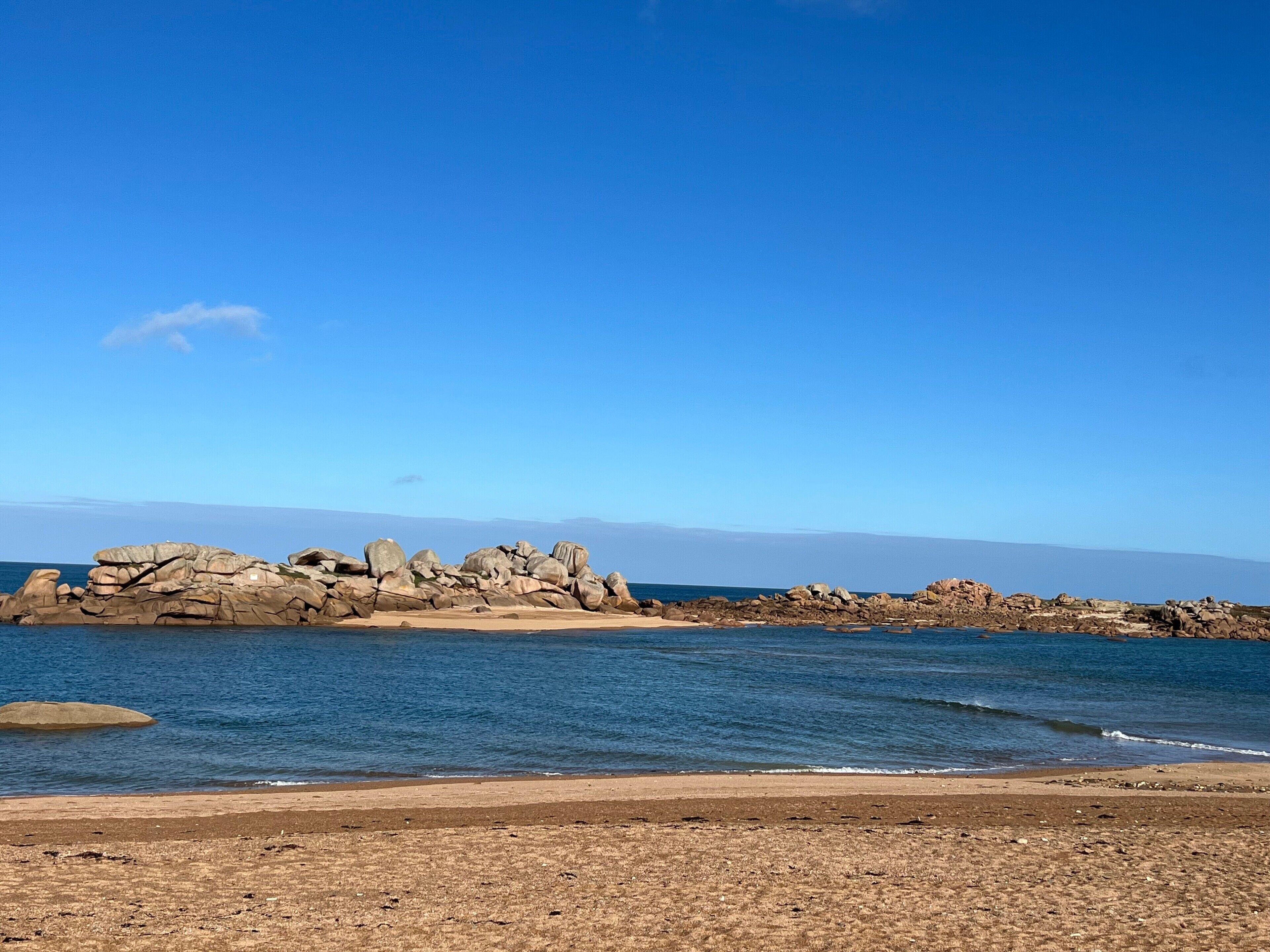 Une plage avec des formations rocheuses et un ciel bleu dégagé.