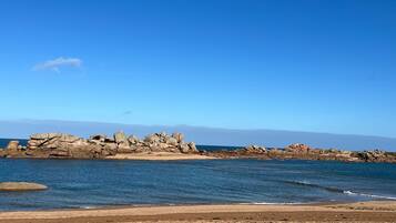 Une plage avec des formations rocheuses et un ciel bleu dégagé.