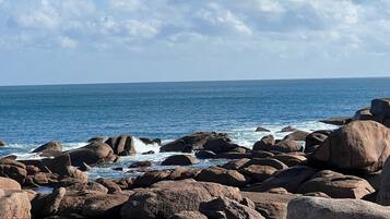 A rocky shoreline with waves crashing against the rocks under a clear sky.