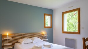 Une chambre à coucher avec un lit, des tables de chevet, une fenêtre et un radiateur.
