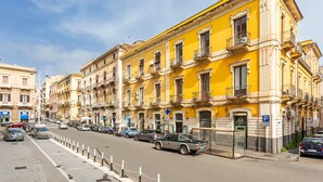 A street view with yellow buildings, parked cars, and a clear sky. - Room 'Il Mappamondo -  Ensuite' with Wi-Fi and Air Conditioning (Catania)