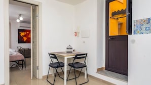 A room with a bed, a dining table with chairs, a small table with a birdcage, a phone, and a door with a decorative panel.