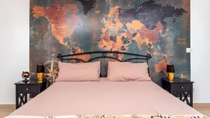 A bed with a world map backdrop, a globe, and a compass on a nightstand.