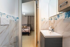 Un baño moderno con lavamanos blanco, espejo y zona de ducha.