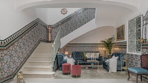 A grand staircase with intricate tile work, a plush seating area with sofas and ottomans, and a large framed artwork on the wall. - Room 'Suite Diamante' with Mountain View, Shared Terrace and Wi-Fi (Alcalá del Valle)