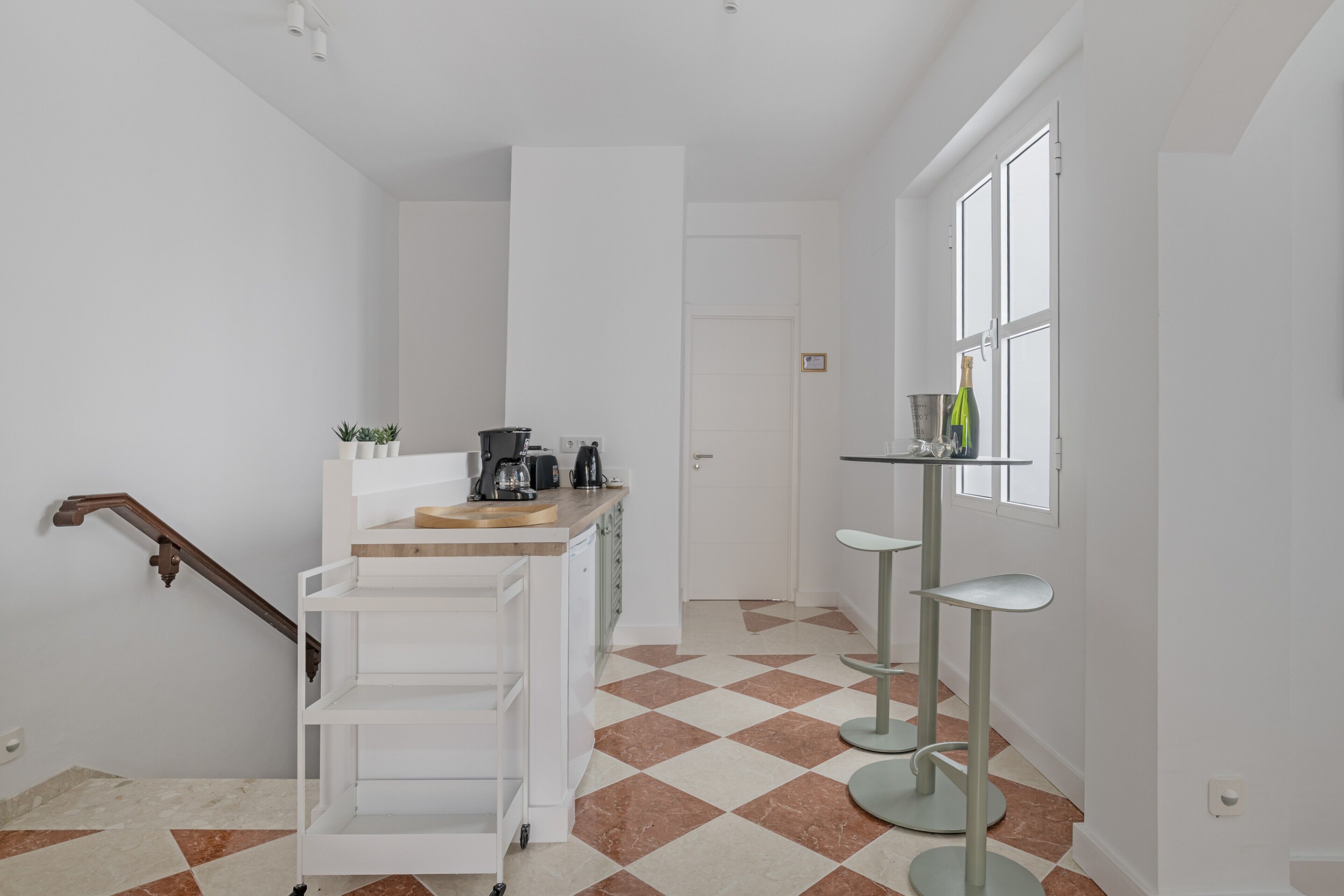 Une cuisine moderne avec un plan de travail en bois, une machine à café et un petit îlot central doté d’un évier.