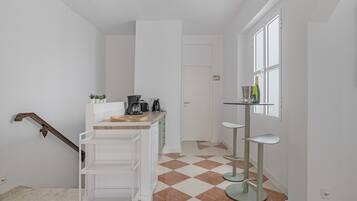 Une cuisine moderne avec un plan de travail en bois, une machine à café et un petit îlot central doté d’un évier.