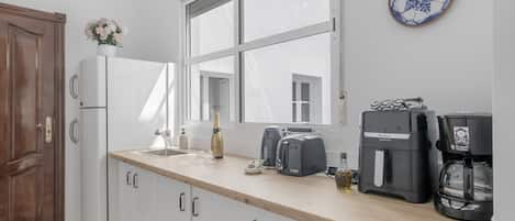 Una cocina con encimera de madera, refrigerador, cafetera y ventana.