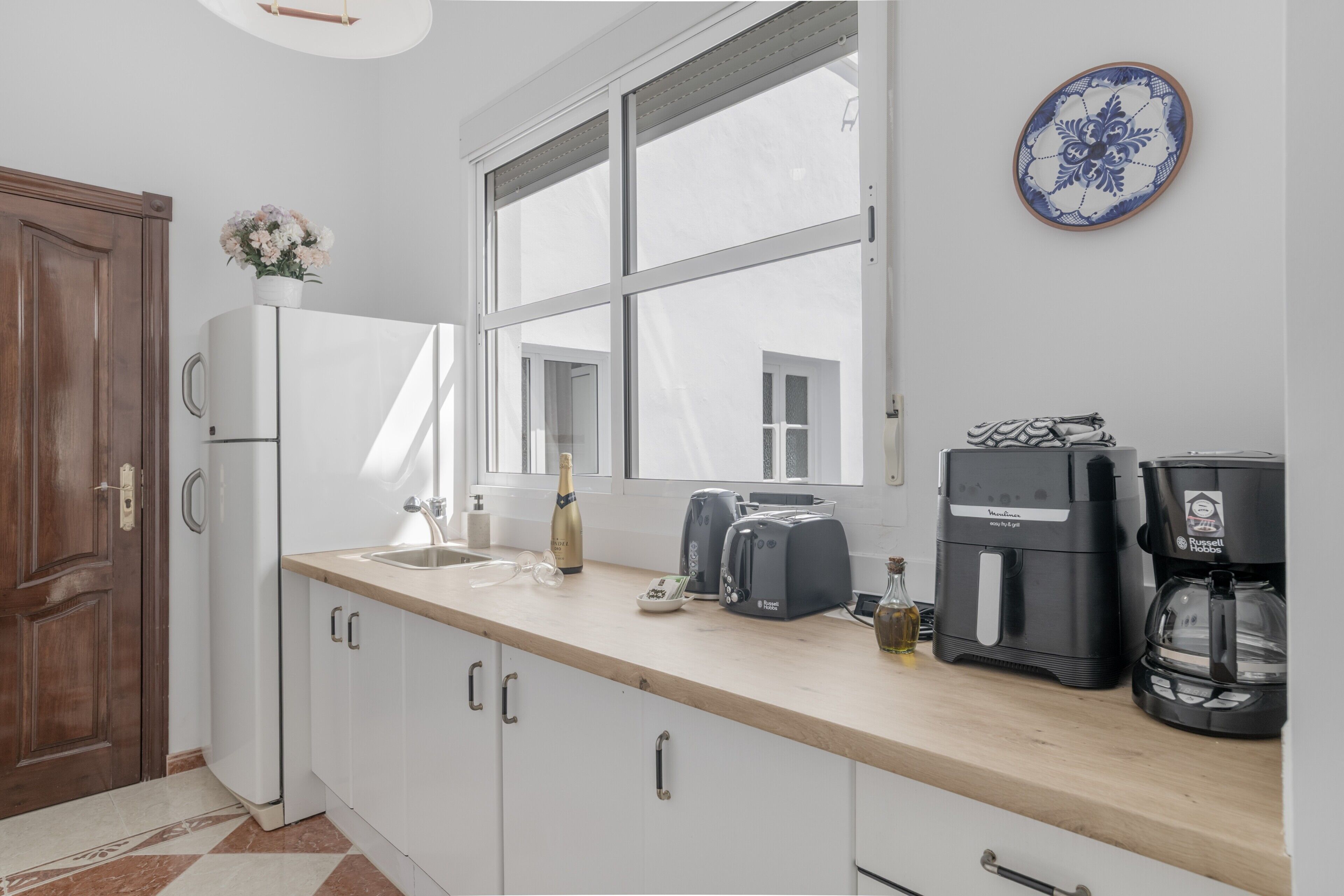 A kitchen with a wooden countertop, a refrigerator, a coffee maker, and a window.