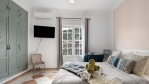 A bedroom with a bed, a chair, a television, and a window with curtains. - 'Topacio' Room with Mountain Views, Shared Terrace and Wi-Fi (Alcalá del Valle)