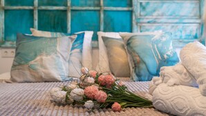 Un letto con una coperta trapuntata, un bouquet di fiori e cuscini decorativi.