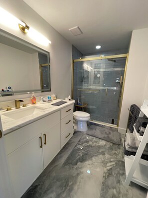 Features a sleek vanity, large mirror, and glass-enclosed shower.
