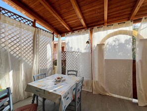 A covered patio area with a table set for dining, featuring a tablecloth with a fish pattern. - Apartment 'La Casetta Di Lulu' with Private Terrace, Private Garden and Air Conditioning (Villasimius)