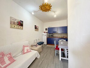 A compact living space with a kitchenette, a dining area, and a bed. - Apartment 'La Casetta Di Lulu' with Private Terrace, Private Garden and Air Conditioning (Villasimius)