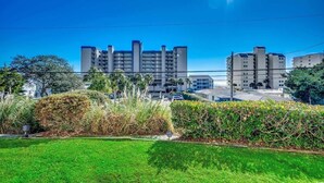 A residential area with modern apartment buildings, a well-maintained lawn, and a clear blue sky.