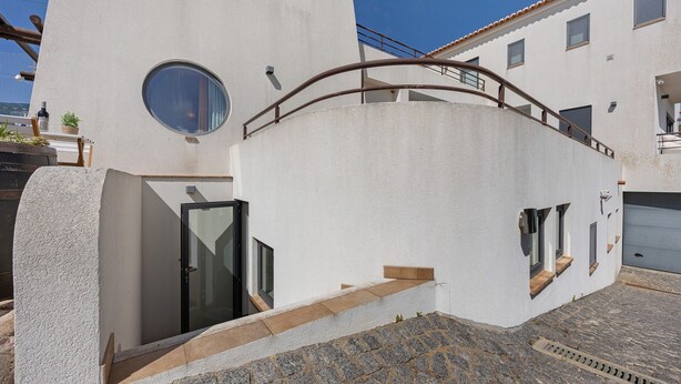 A modern building with a circular window, a staircase, and a garage.