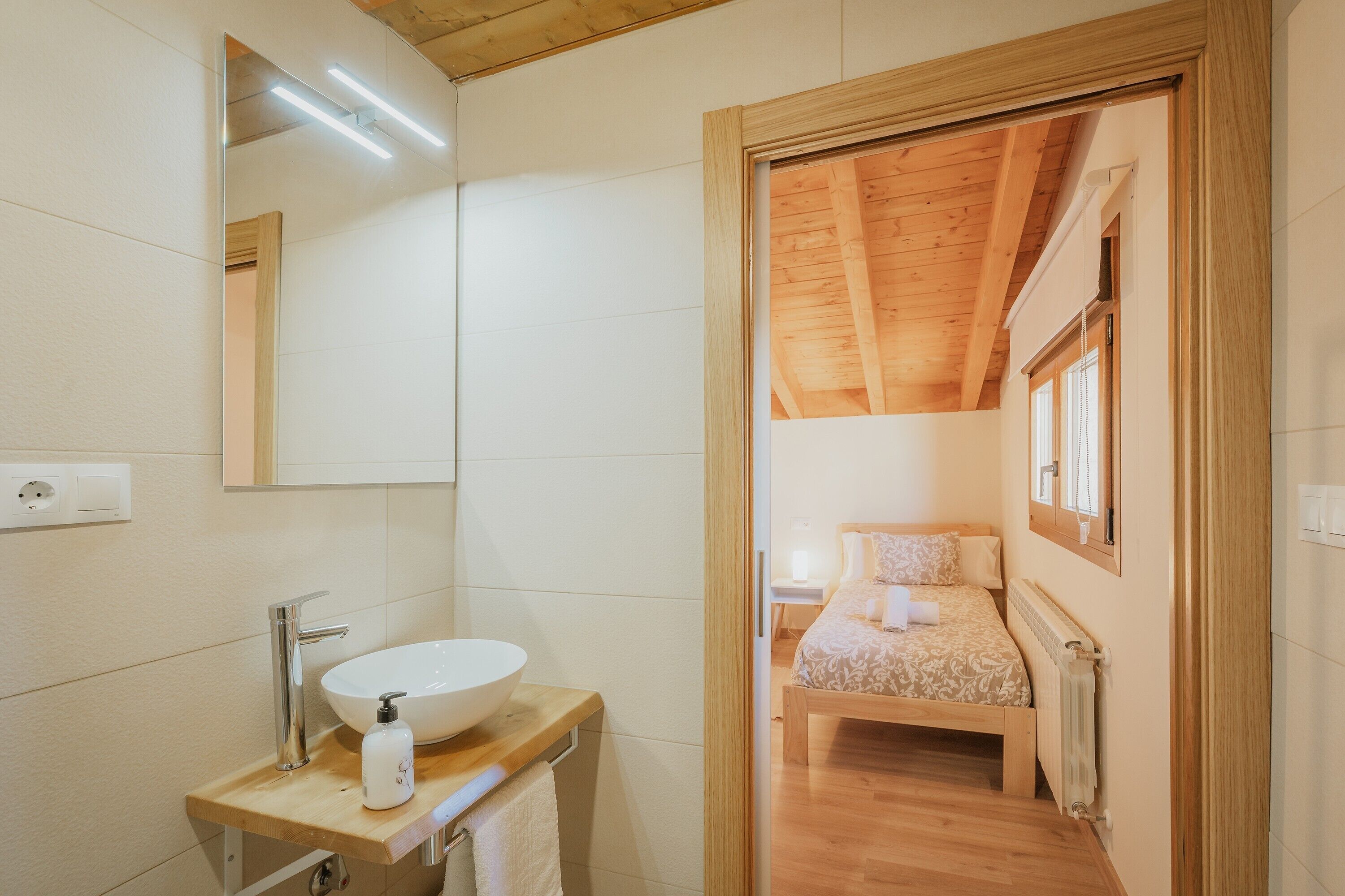 Une salle de bain avec un lavabo blanc, un miroir et un meuble-lavabo en bois.