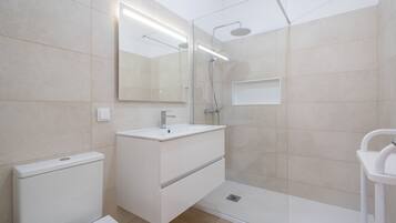 A modern bathroom with a shower, sink, and toilet.