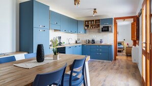 Een moderne keuken met blauwe kastjes, een houten eettafel en een keukenbar.