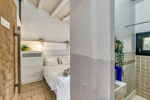 Quarto com cama, mesa de cabeceira e janela.