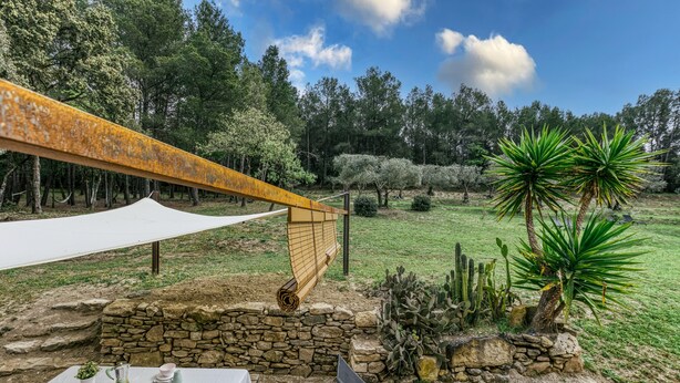 A table set outdoors with a white tablecloth, a stone wall, and a hammock.