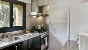A modern kitchen with stainless steel appliances, a window with a view of trees, and a built-in oven.