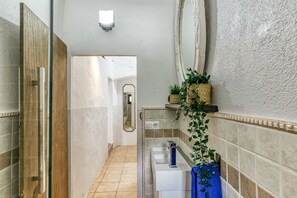 Un bagno con una porta in legno, uno specchio, un lavandino e una pianta.