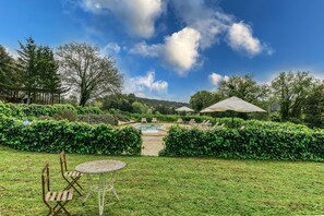 Um quintal com piscina, cadeiras e uma mesa.