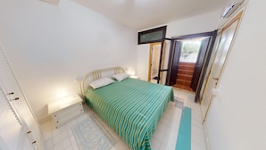 A bedroom with a bed, a nightstand, a wall-mounted TV, and a door leading to a balcony. - Villa 'Ersilia' with Sea View, Wi-Fi and Air Conditioning (Campulongu)