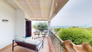 A balcony with a sofa, two chairs, a small table, and a view of the sea. - Villa 'Ersilia' with Sea View, Wi-Fi and Air Conditioning (Campulongu)