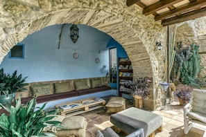 A rustic stone interior with a bench, a table, and a bookshelf.