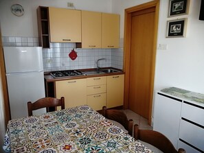Una cucina compatta con frigorifero, fornello, lavello e mobili in legno.