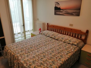 Une chambre à coucher avec un lit, une table de chevet, une lampe, un radiateur et un tableau au mur.