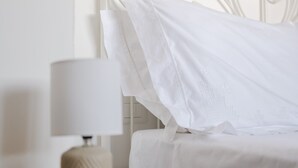 A neatly made bed with white linens, a bedside table with a lamp, and a white headboard. - Room 'Domenica' with Private Terrace, Wi-Fi and Air Conditioning (Carovigno)