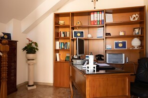 Un bureau bien aménagé, avec un bureau en bois, un ordinateur, une imprimante et une bibliothèque.