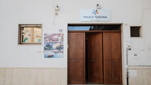 A building entrance with a wooden door, a sign reading 'Piazza 'N'Zegna Bed & Bread,' and a small window with papers. - Room 'Lunedì' with Balcony, Wi-Fi and Air Conditioning (Carovigno)