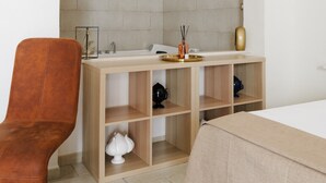 A room with a stone archway, a wooden bench, a table with a cloth, a sink, and a cabinet.