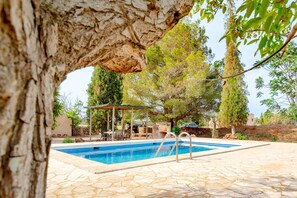 A swimming pool with a stone deck, surrounded by trees and a pergola. - Country House 'Espina' with Private Pool, Private Terrace and Wi-Fi (Illes Balears)