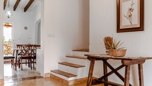A staircase leading to a dining area with wooden chairs and a table with a basket of dried plants.