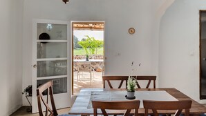 A dining area with a table and chairs, a potted plant, a ceiling light, and a view of an outdoor patio.