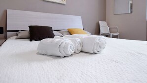 A neatly made bed with rolled white towels, a brown pillow, and a yellow pillow. - Room 'Swan Matrimoniale Brown' with Shared Pool, Wi-Fi and Air Conditioning (Manerba del Garda)