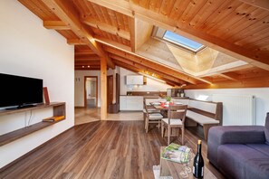 A modern loft-style room with a wooden ceiling, a dining area, a kitchen, and a living room with a flat-screen TV and seating. - Apartment 'Zeppenhof' with Mountain View, Private Terrace and Wi-Fi (Santa Valburga St. Walburg)