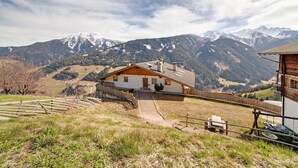 A mountain lodge with a wooden exterior, a paved driveway, and a view of snow-capped mountains.
