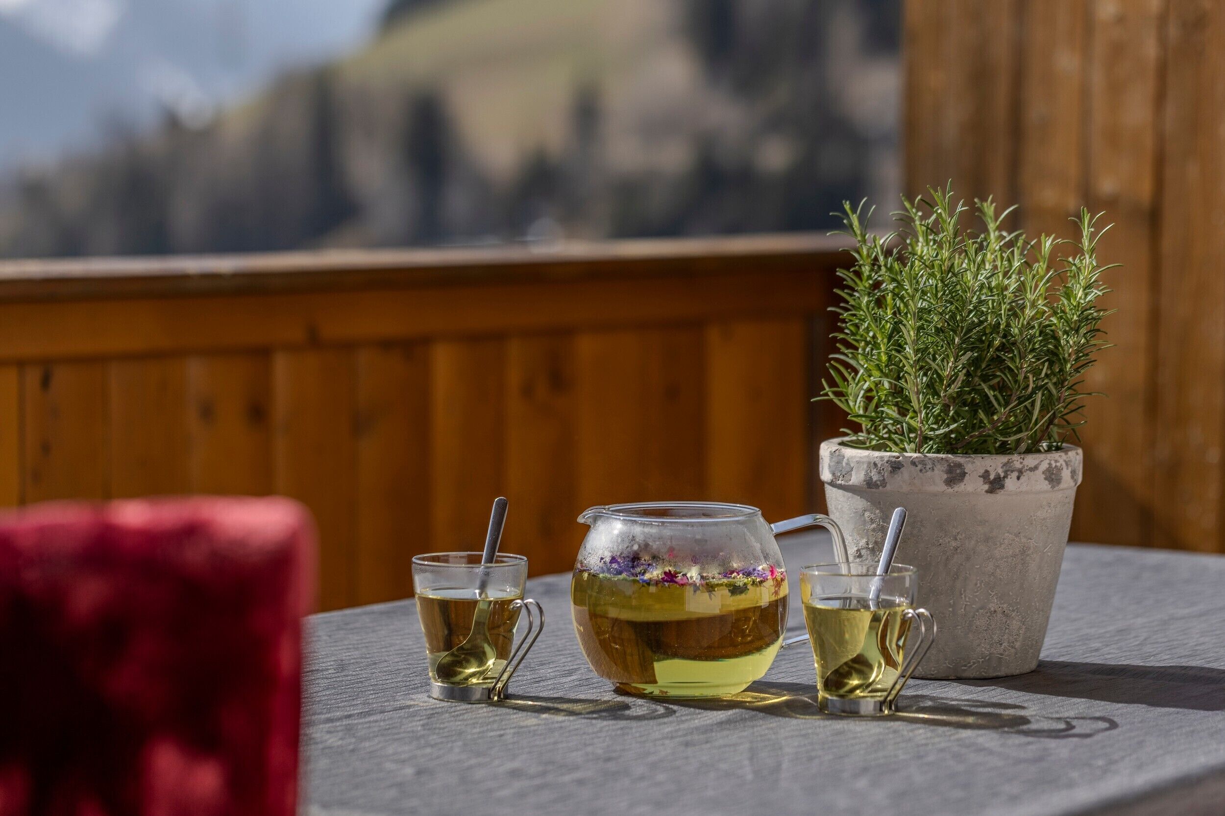 A table with a teapot, two cups, and a potted plant.