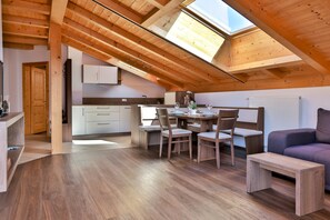 A loft-style room with a skylight, wooden beams, a dining area with chairs, a small table, and a sofa. - Apartment 'Zeppenhof' with Mountain View, Private Terrace and Wi-Fi (Santa Valburga St. Walburg)