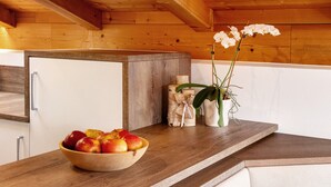 A wooden countertop with a bowl of fruit, a vase with flowers, and a small wooden cabinet.